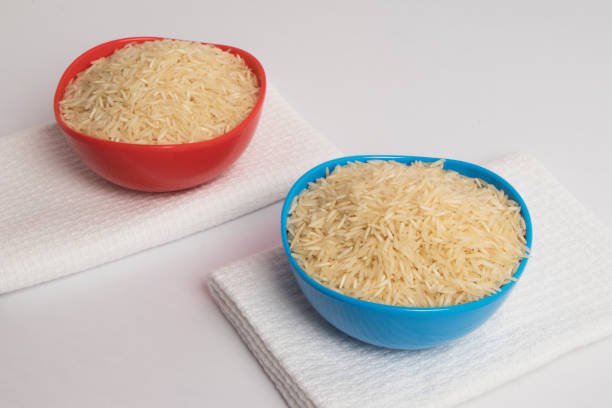 Red and blue rice bowls full of basmati rice kept on basmati rice.