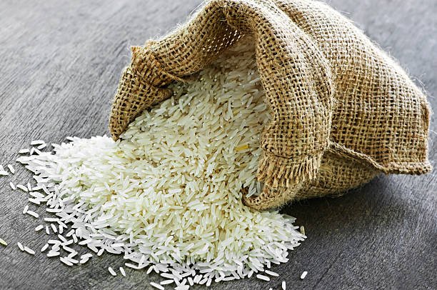 Raw long grain white rice grains in burlap bag