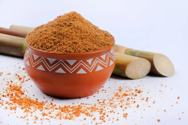 Jaggery powder and sugarcane isolated on white background. Jaggery is used as an ingredient in sweet and savoury dishes in the cuisines of India. Selective focus.